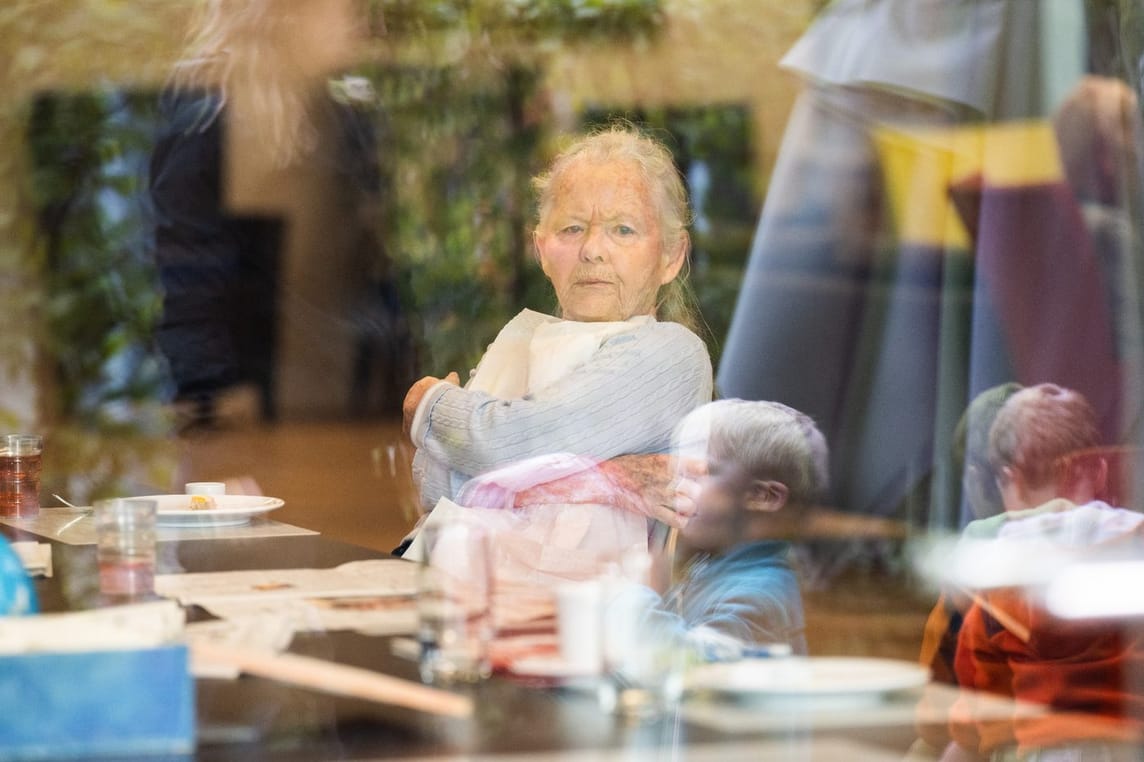 Die Dame beobachtet die Kinder beim Spiel im Garten durch die Scheibe.