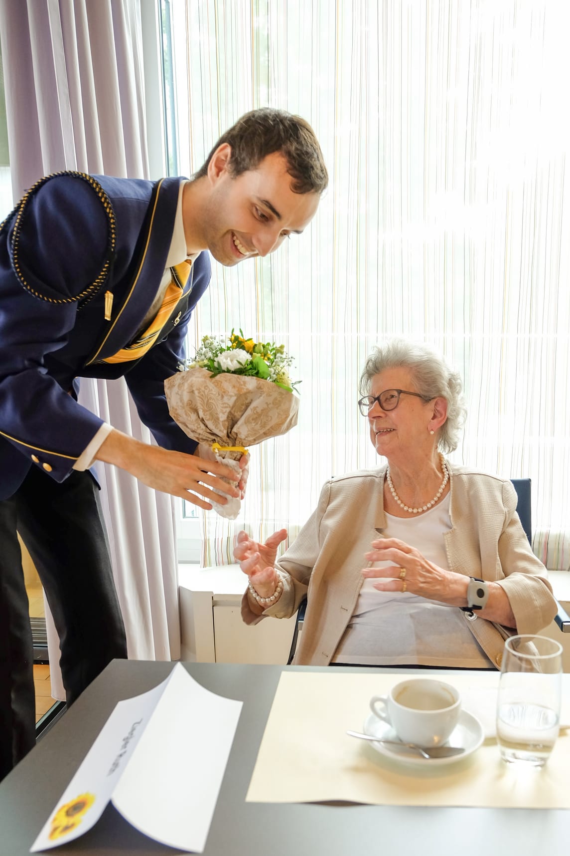 Die Bewohnerin wird mit Blumen beschenkt.