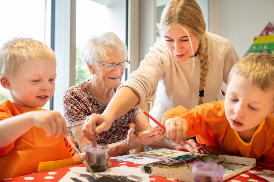 An den Nachmittagen finden ganz unterschiedliche Aktivitäten statt - und da in unterschiedlicher Zusammensetzung. Wenn es passt, kommen Bewohnende und Kinder für eine Tätigkeit zusammen. Hier wird mit Fingerfarben gemalt. Eine Dame mag sich heute kreativ mit den Kindern betätigen.