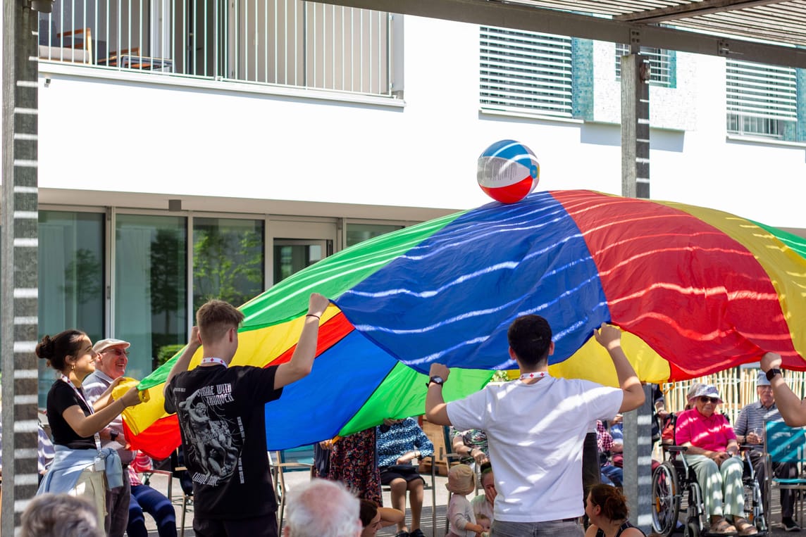 Mit dem Farbentuch spielten die 14 Lernenden der Hostettler Group einen Ball in die Luft. Die Bewohnerinnen und Bewohner erfreuten sich an der Attraktion.